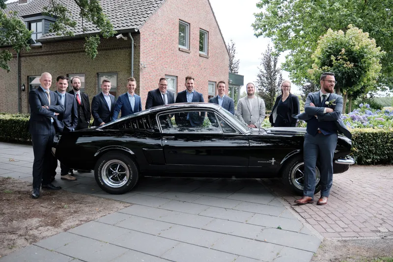 Barry en zijn vrienden in pak naast de zwarte Mustang
