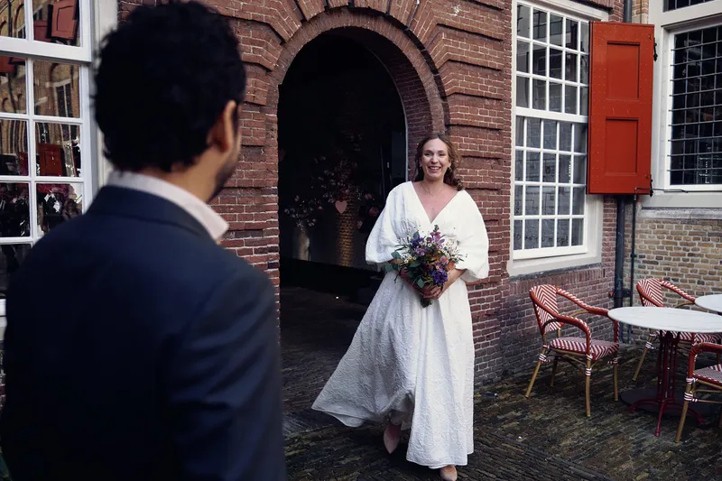 Raphaël van achteren, Anouk loopt naar hem toe uit de boogdeur