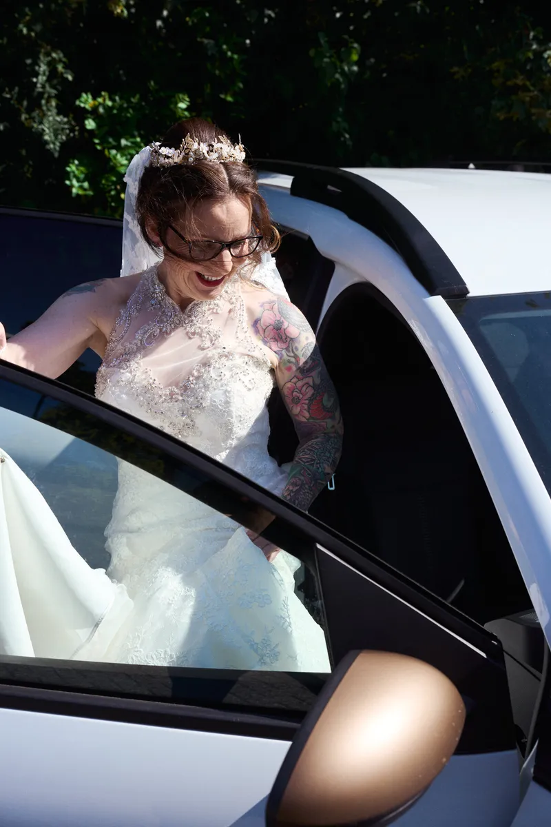 Karon stapt in de auto, met de sluier om zich heen