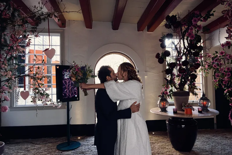 Anouk en Raphaël omarmen elkaar in de lobby, tussen de bloemen en hartjes
