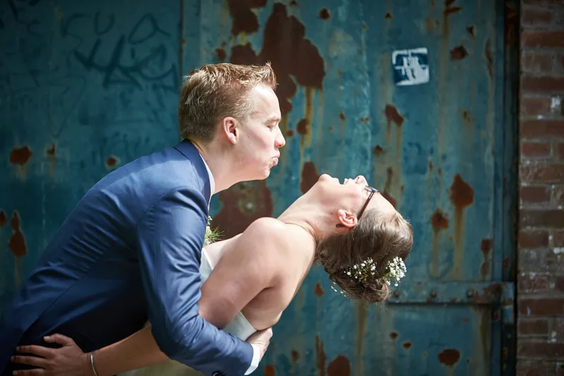 Coen buigt Marjolein achterover voor een verweerde blauwe deur