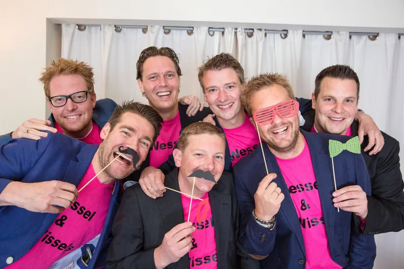 Een groep vrienden in roze shirts in de fotobooth