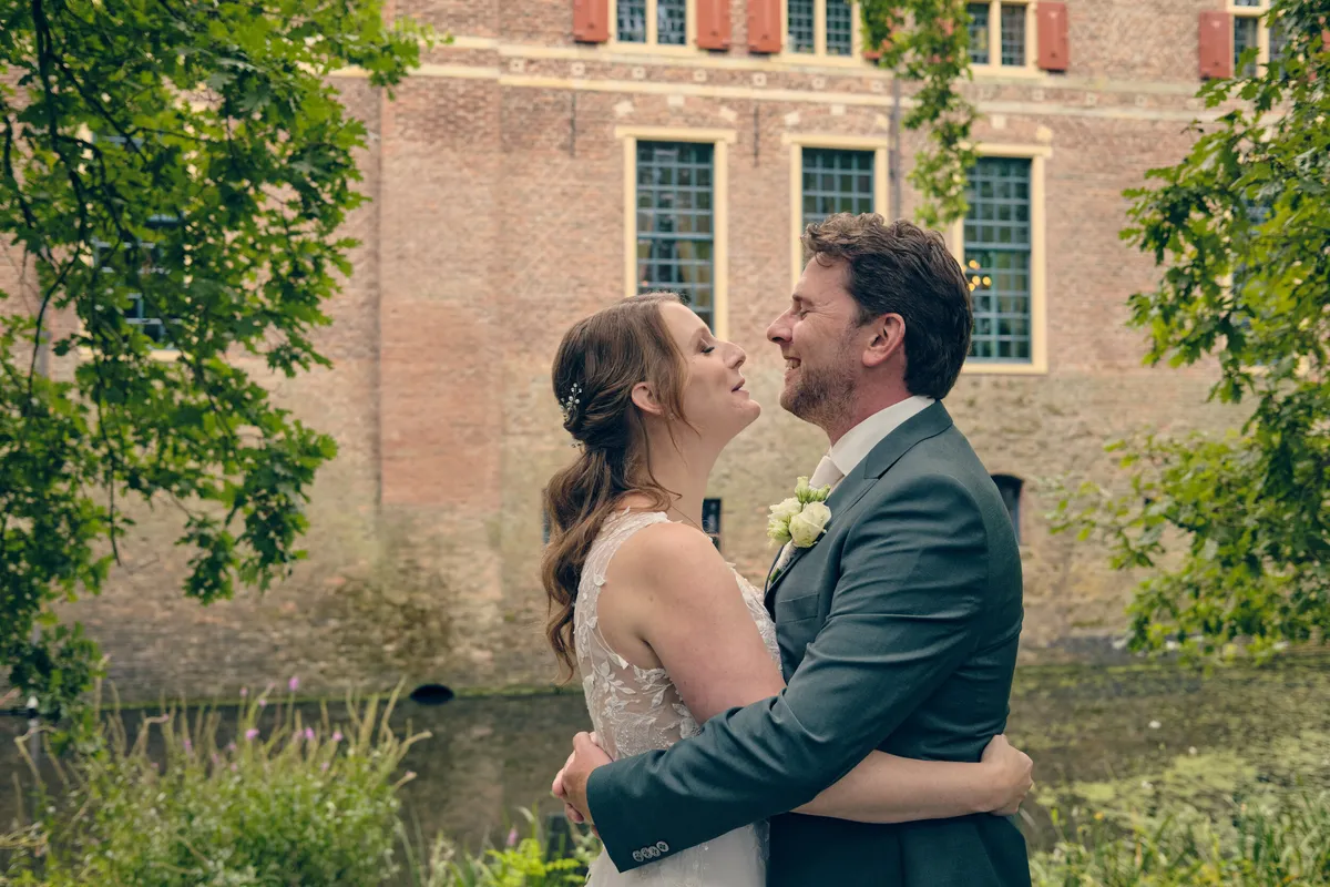 Fabian en Renée kussen elkaar aan de gracht voor het kasteel