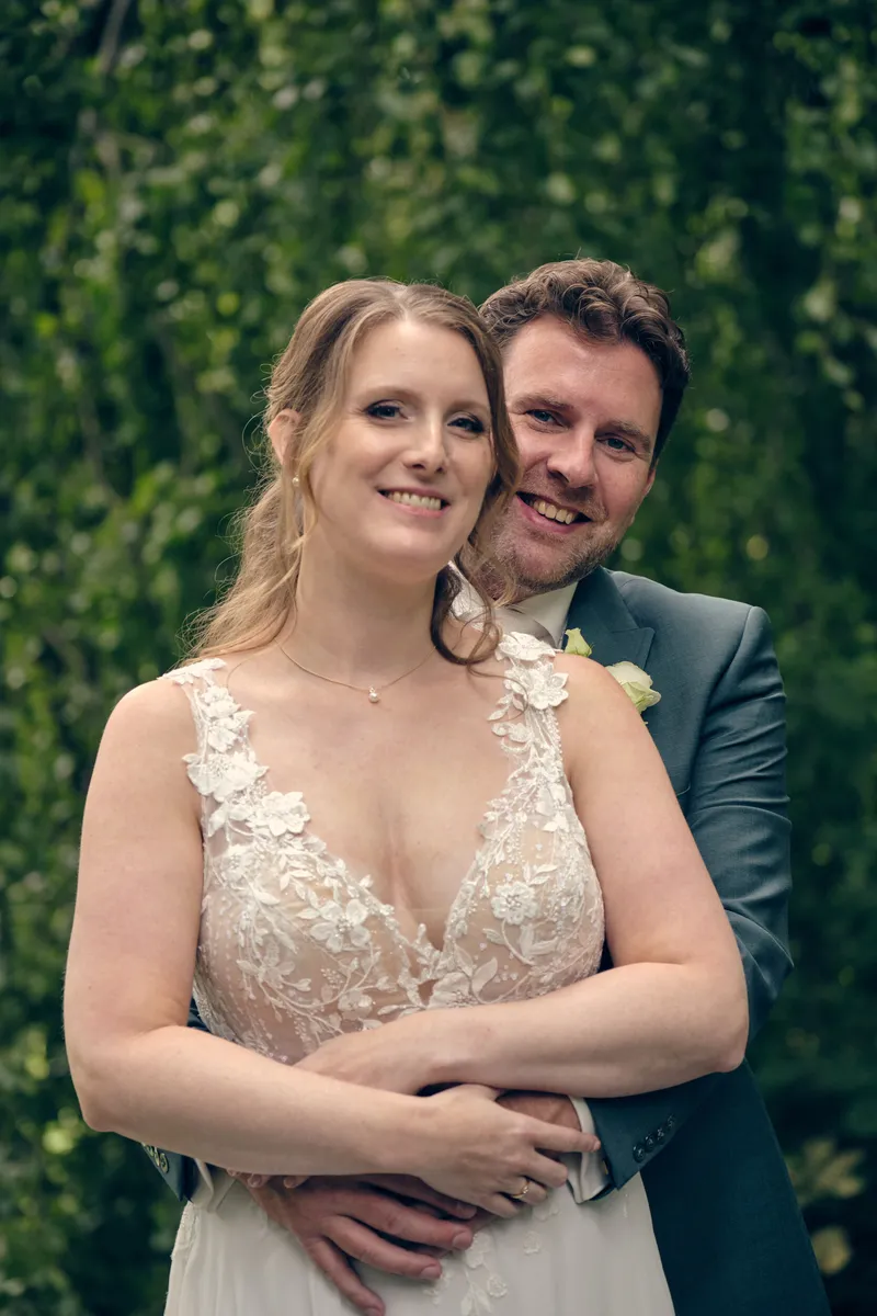 Fabian slaat zijn armen om Renée heen voor een groene haag