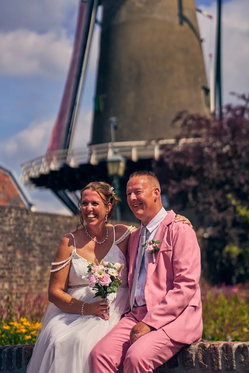 Diliana en Olav op de muur onder de wieken van molen De Windotter