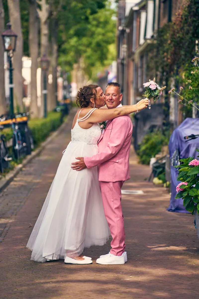 Diliana en Olav kussen elkaar in een straatje met bomen