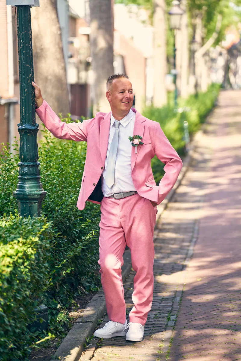 Olav leunt tegen een lantaarnpaal in zijn roze pak