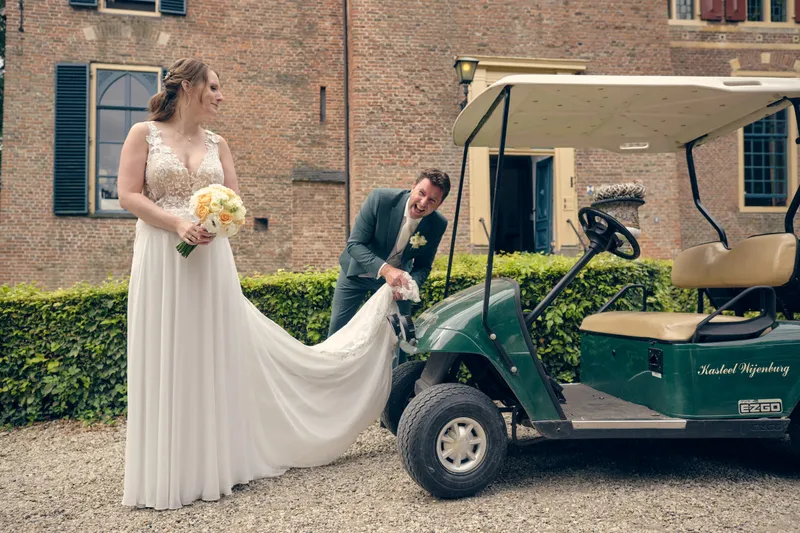 Fabian schikt de sleep van Renée naast het golfkarretje van het kasteel