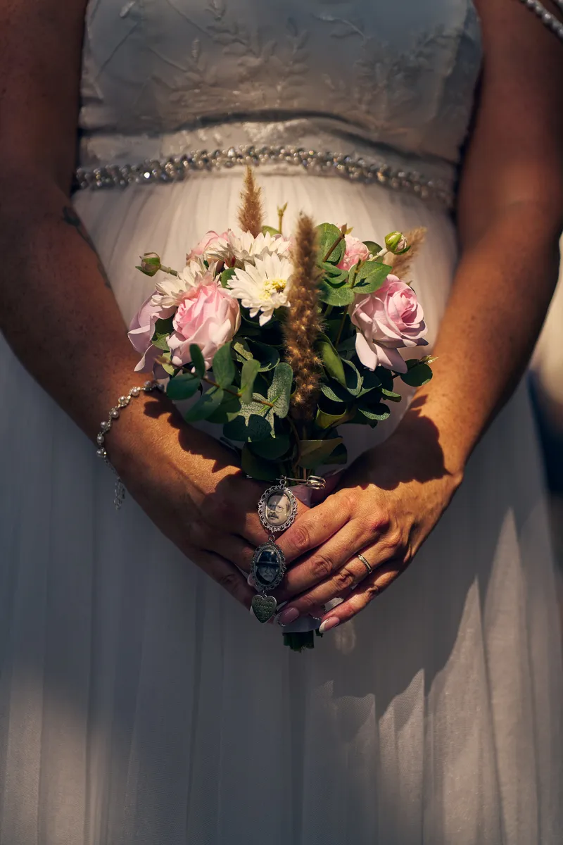 Diliana houdt haar boeket vast, met twee medaillons met foto’s van hun vaders eraan