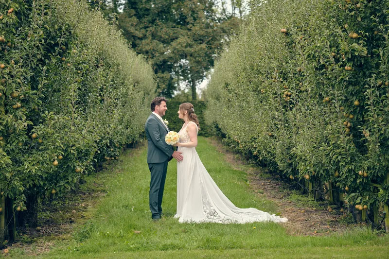 Fabian en Renée tussen de lange rijen fruitbomen in de boomgaard