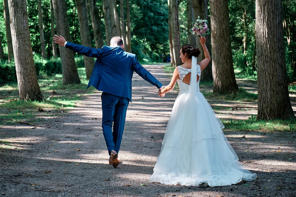 Jeroen springt van blijdschap in een laan met hoge bomen, Tessa loopt naast hem