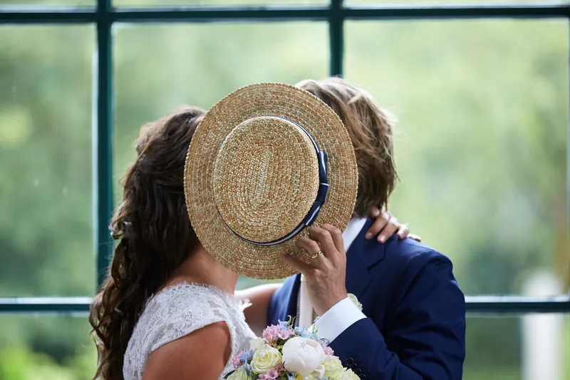 Rinkje en Wouter kussen achter zijn strohoed