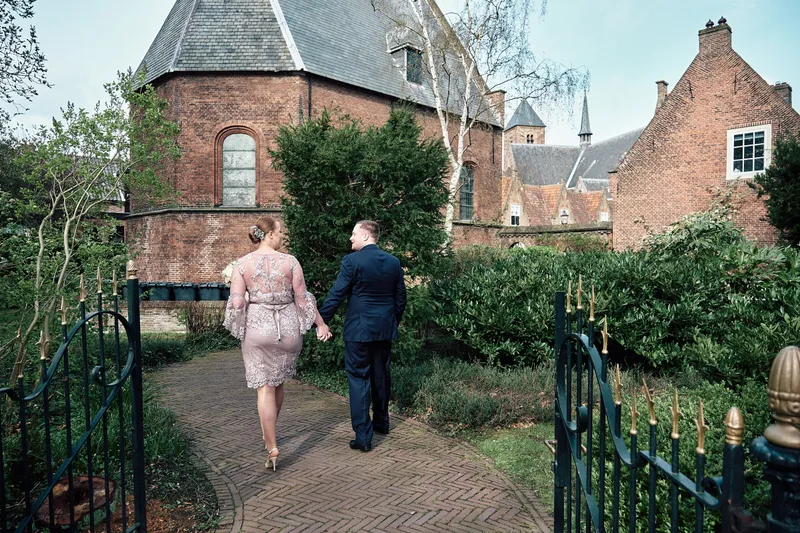 Maddy en Wijnand lopen door het hek naar de kapel van het hofje