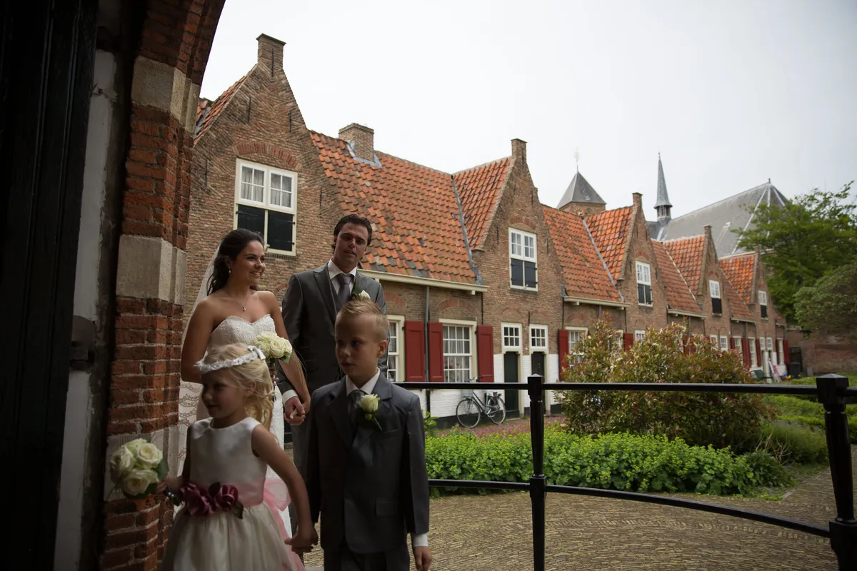 Jeroen en Margriet komen met twee kinderen het hofje binnen, met de lage huisjes en de tuin erachter