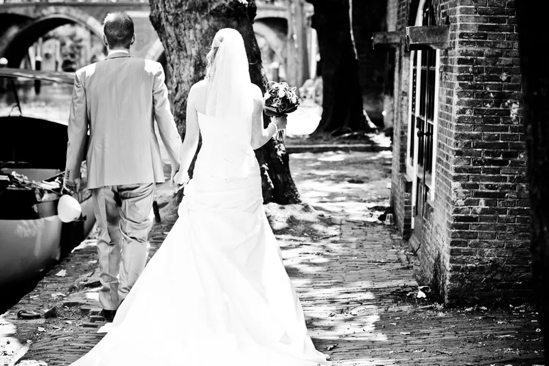 Loes en Jan lopen hand in hand langs de gracht, van achteren gezien, in zwart-wit