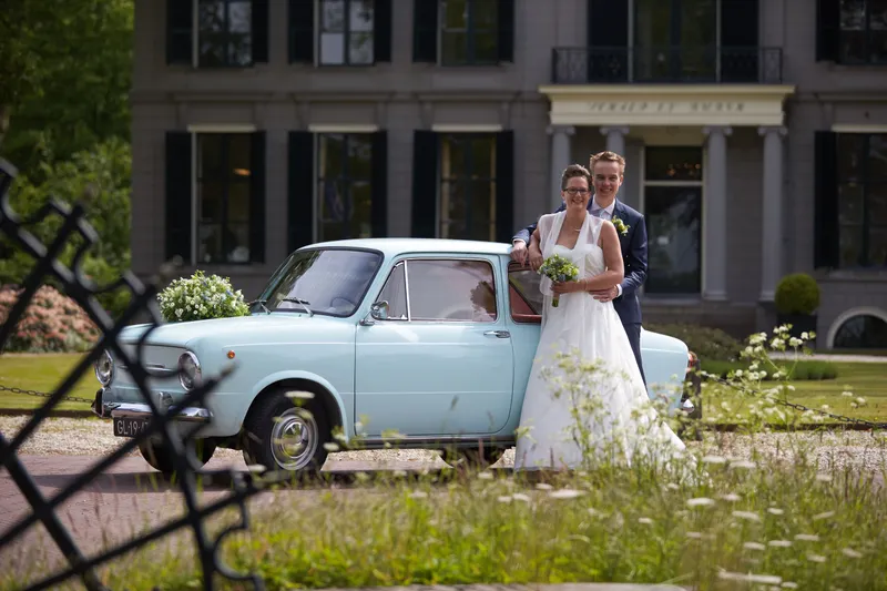 Marjolein en Coen bij de blauwe Fiat 850 voor het landhuis in ’s-Graveland