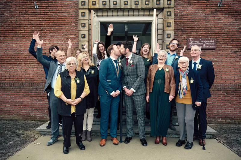 De groepsfoto bij de ingang van de kerk, een gast steekt zijn armen in de lucht