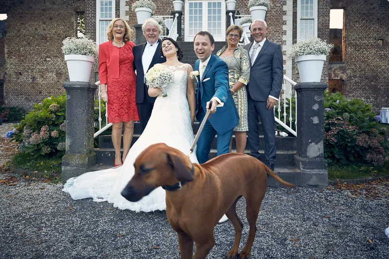 Familie met het bruidspaar en de hond voor de trap van het kasteel