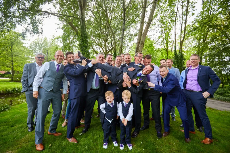 Robbert met zijn vrienden en twee jongetjes in pak op het gazon