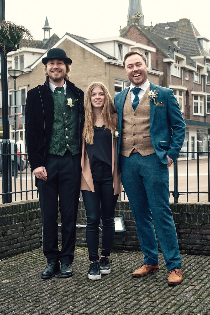 Een bruidegom met twee vrienden bij het hek