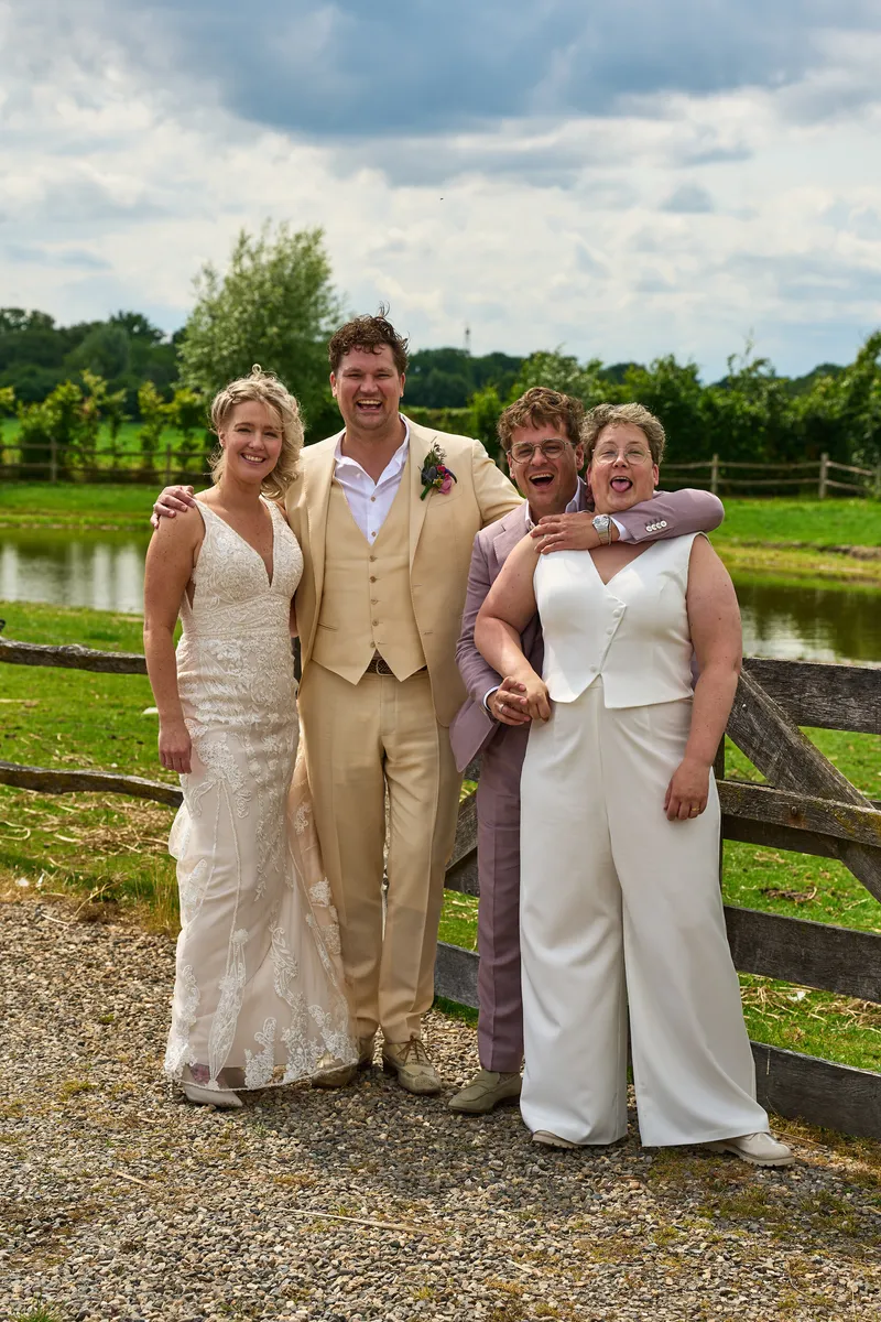 Froukje en Mireille met een gast in een crèmekleurig pak bij het houten hek