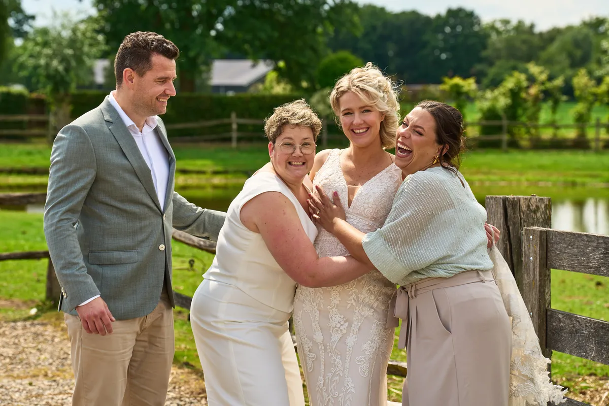 Froukje en Mireille knuffelen met twee gasten bij het hek aan het water