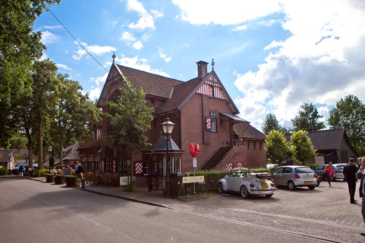 Het Wapen van Haarzuylen met rood-witte luiken, de witte Kever staat ervoor