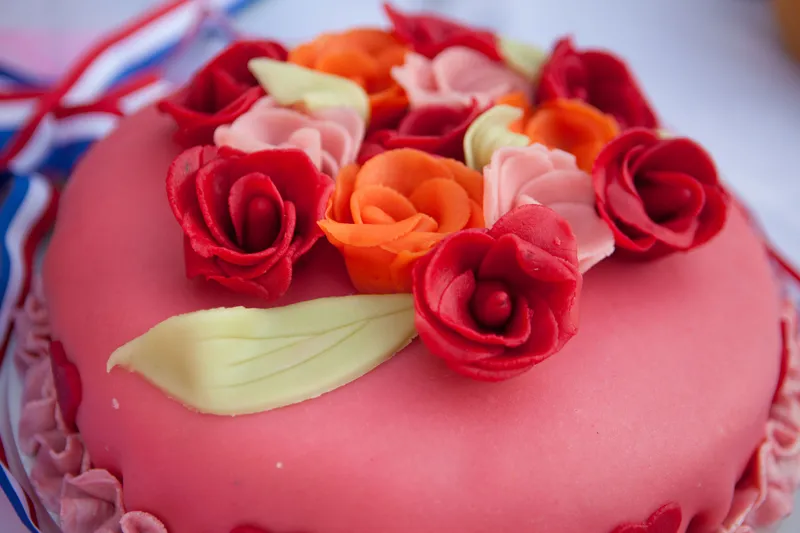 De roze bruidstaart met rode en oranje rozen