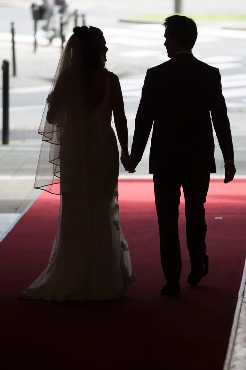 Debora en Joris hand in hand op de rode loper, als silhouet