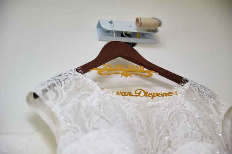 De trouwjurk aan een hanger met de nieuwe naam in gouden letters