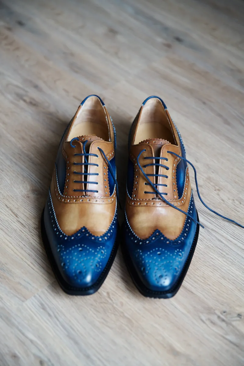 De blauw-bruine schoenen van Herman op de houten vloer