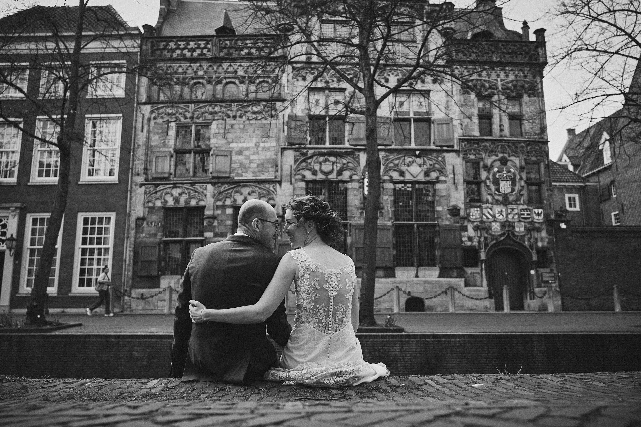 Ilse en Robbert zitten aan de gracht in Delft, voor een historisch pand