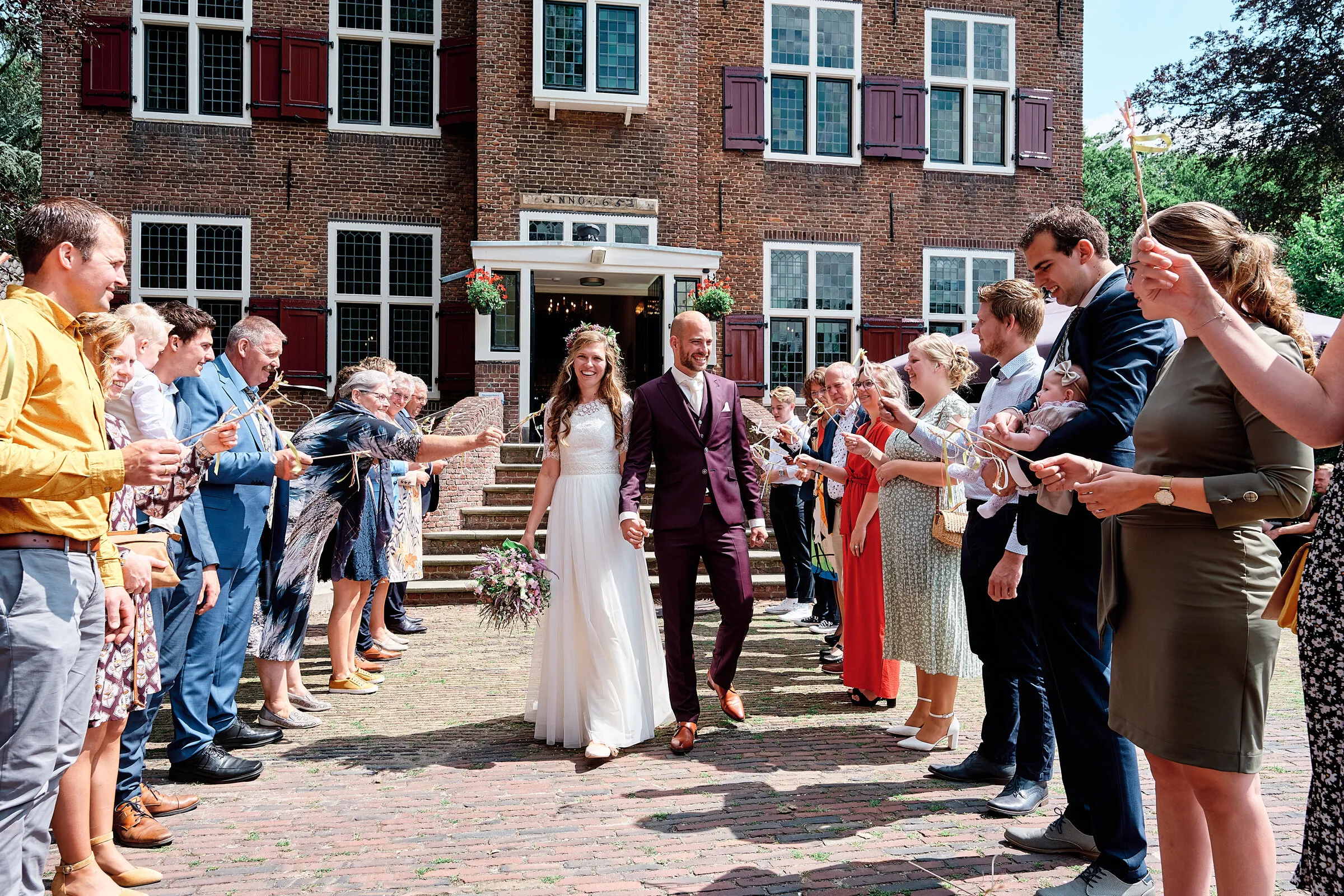 Simon en Mariëth lopen door een erehaag van gasten voor Kasteel Essenburgh in Hierden
