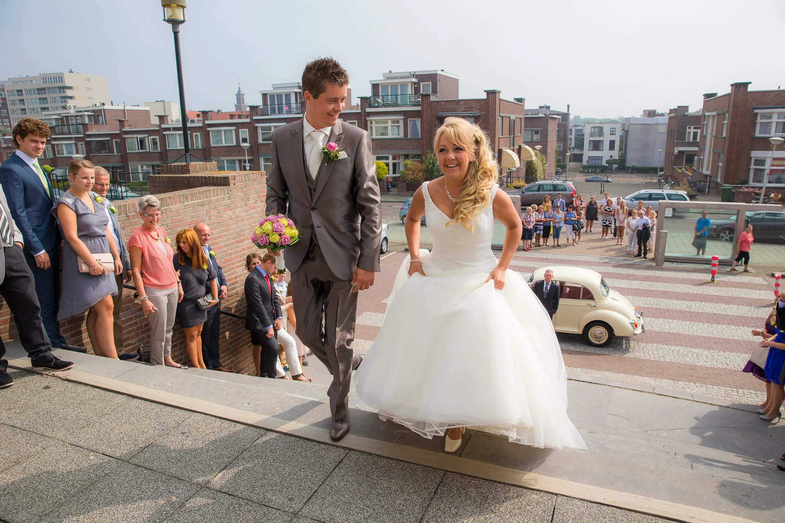 Linda en Alex komen aan bij Paviljoen De Witte in Scheveningen, de gasten op de trap