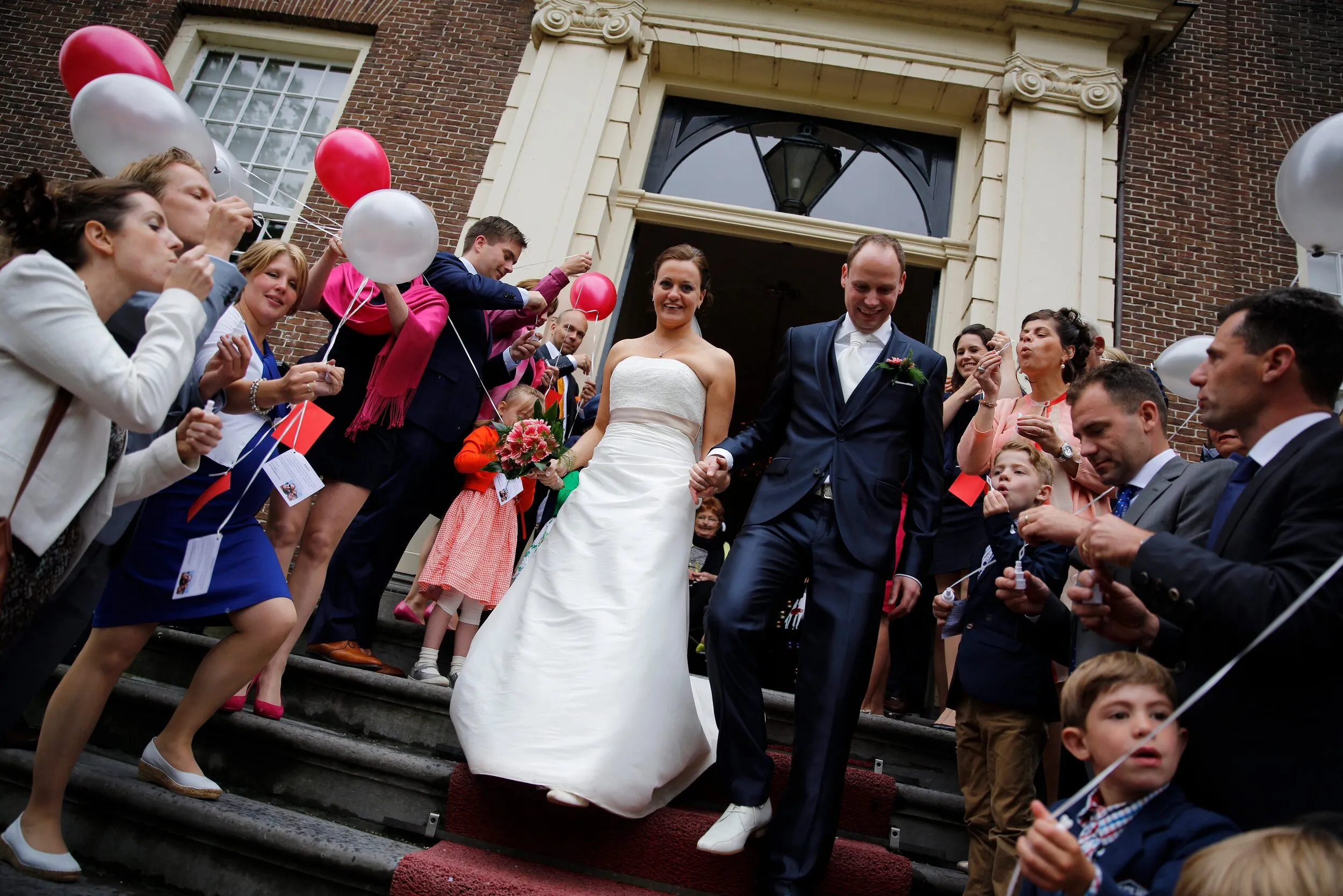 Tessa en Wessel komen de trap van Goudestein af, tussen de gasten met ballonnen