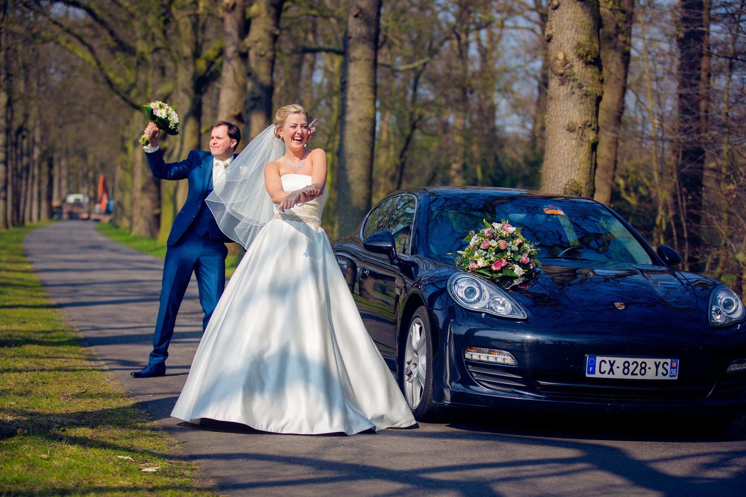 Danielle en Benjamin bij een blauwe sportwagen in de oprijlaan van Kasteel Duivenvoorde