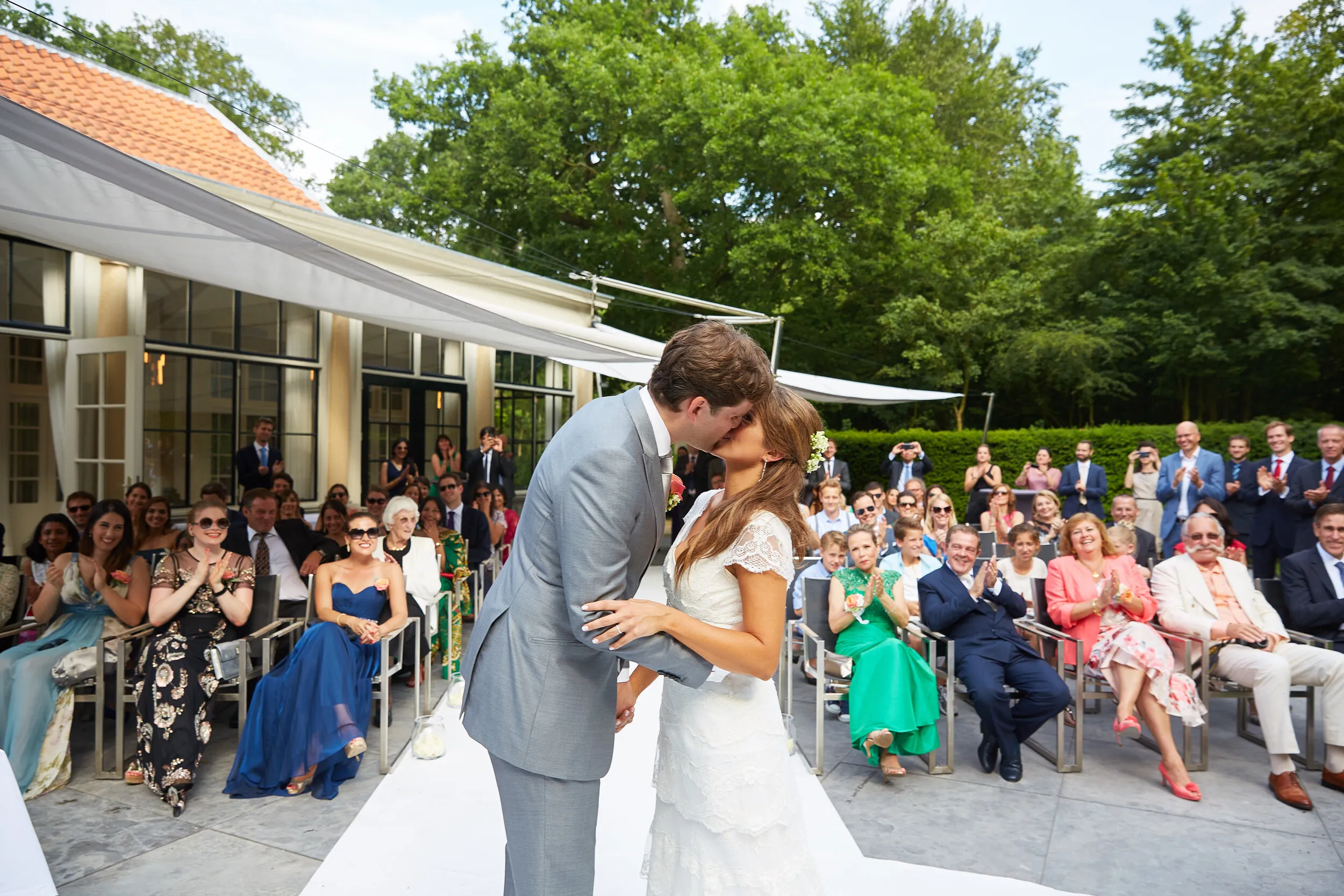 Thais en Vincent kussen op het witte pad op Landgoed Groenendael, met de gasten om hen heen