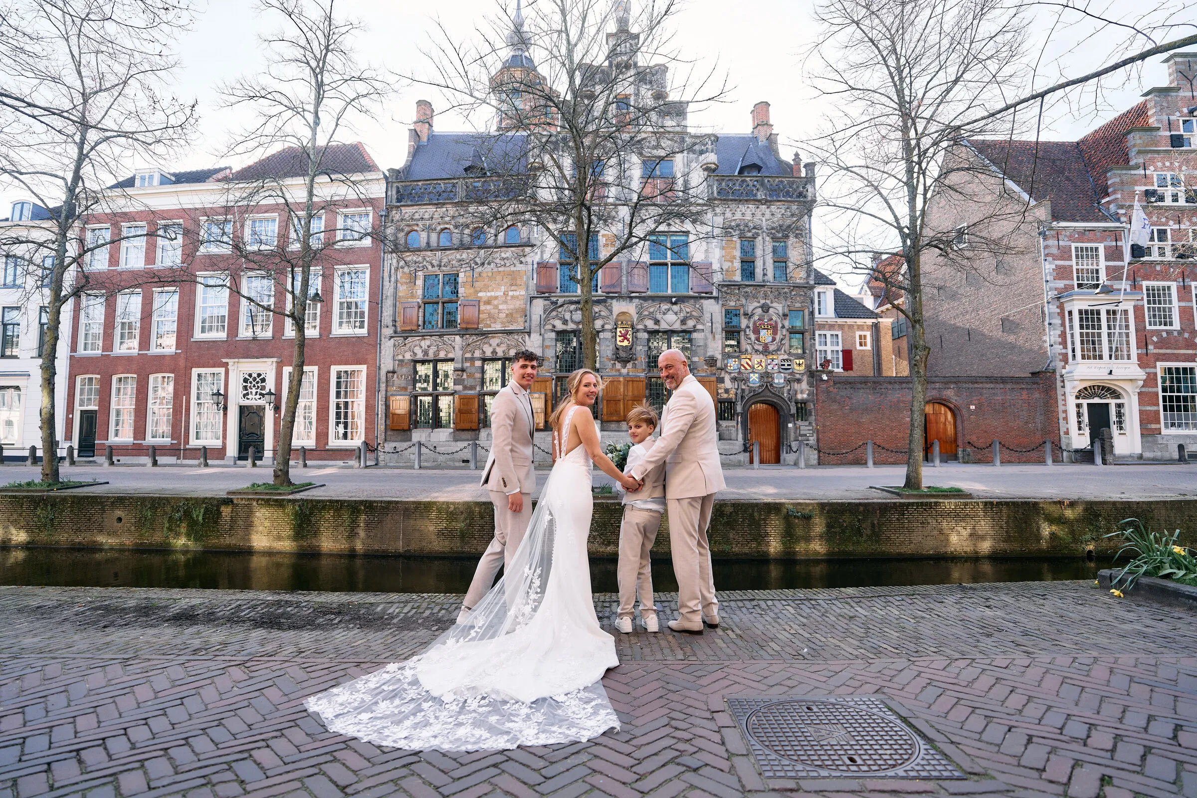 Danitsja en Brian aan de gracht in Delft, met de lange sleep op de klinkers en de oude gevels aan de overkant