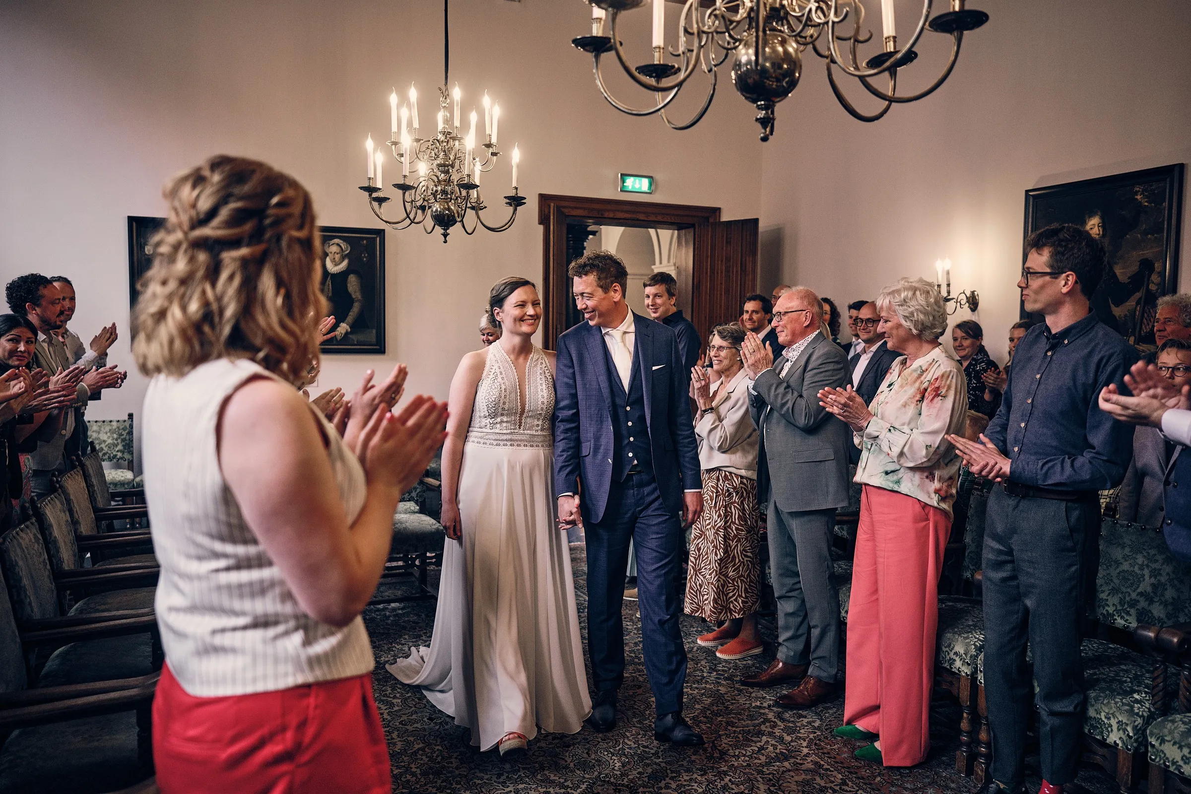 Bruidspaar loopt na de ceremonie hand in hand door een rij klappende gasten