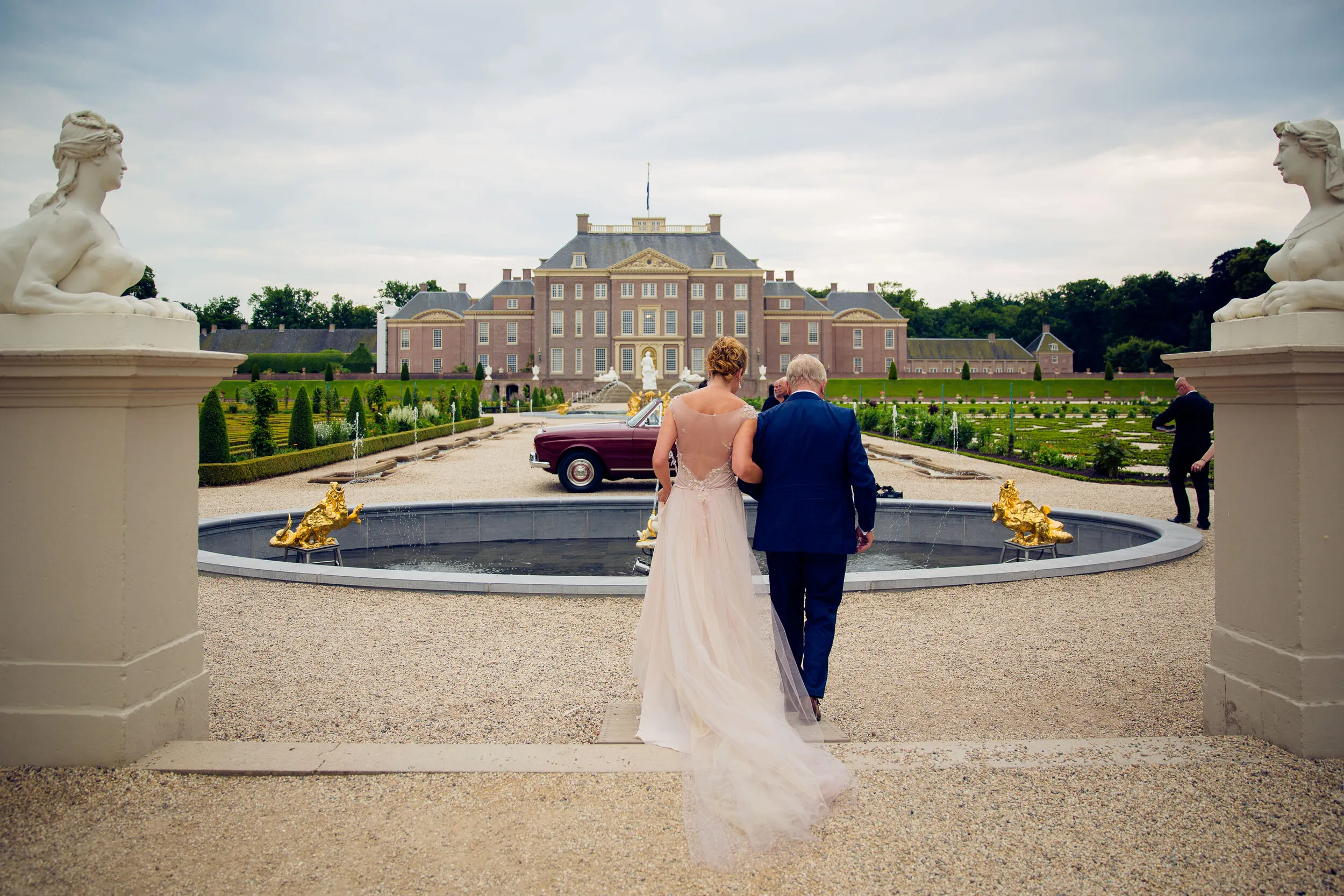 Willem en Jaqueline lopen de trap af, met Paleis Het Loo op de achtergrond