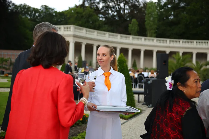 Een ober met een oranje das serveert drankjes