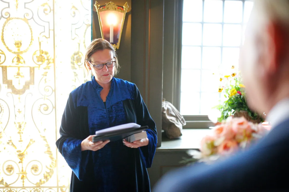 De trouwambtenaar leest voor in een zaal met goud aan de wanden