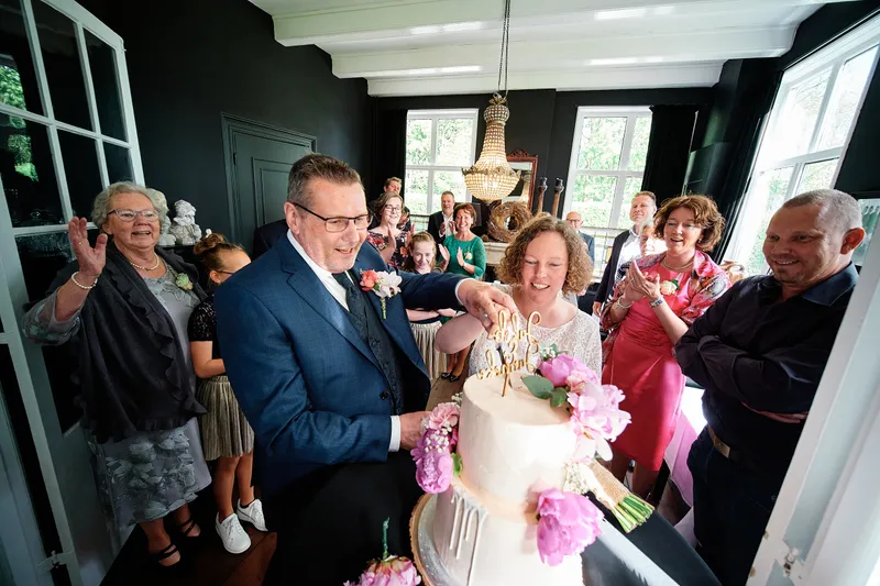 Jakob en Janneke snijden de taart aan tussen de gasten