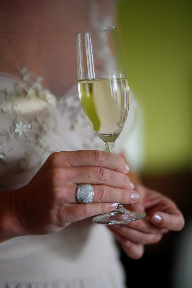 Een hand met ring en een glas champagne