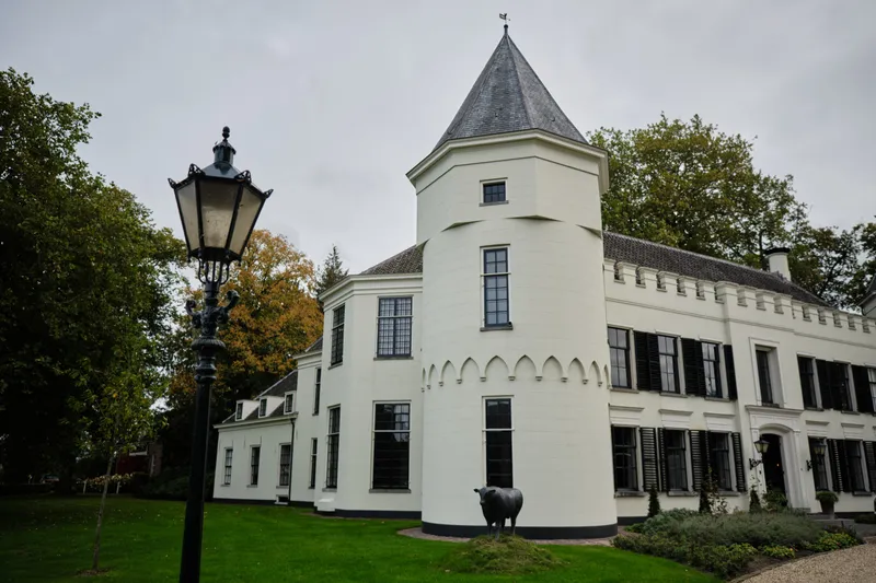 Huis de Salentein met zijn witte gevel en het torentje, een lantaarnpaal op het gras