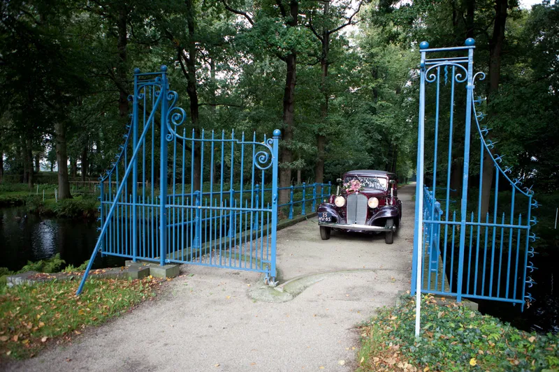De oldtimer tussen de blauwe hekken bij de ingang van het kasteel