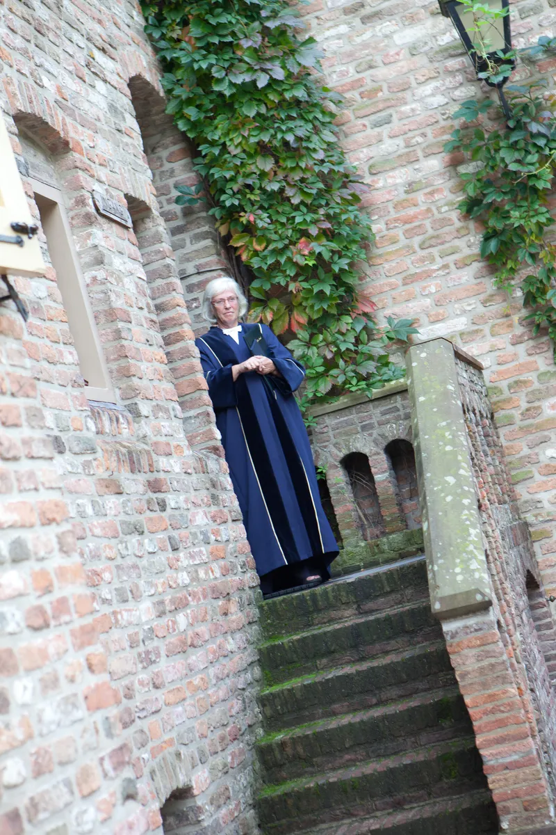De trouwambtenaar wacht bovenaan de stenen trap van het kasteel