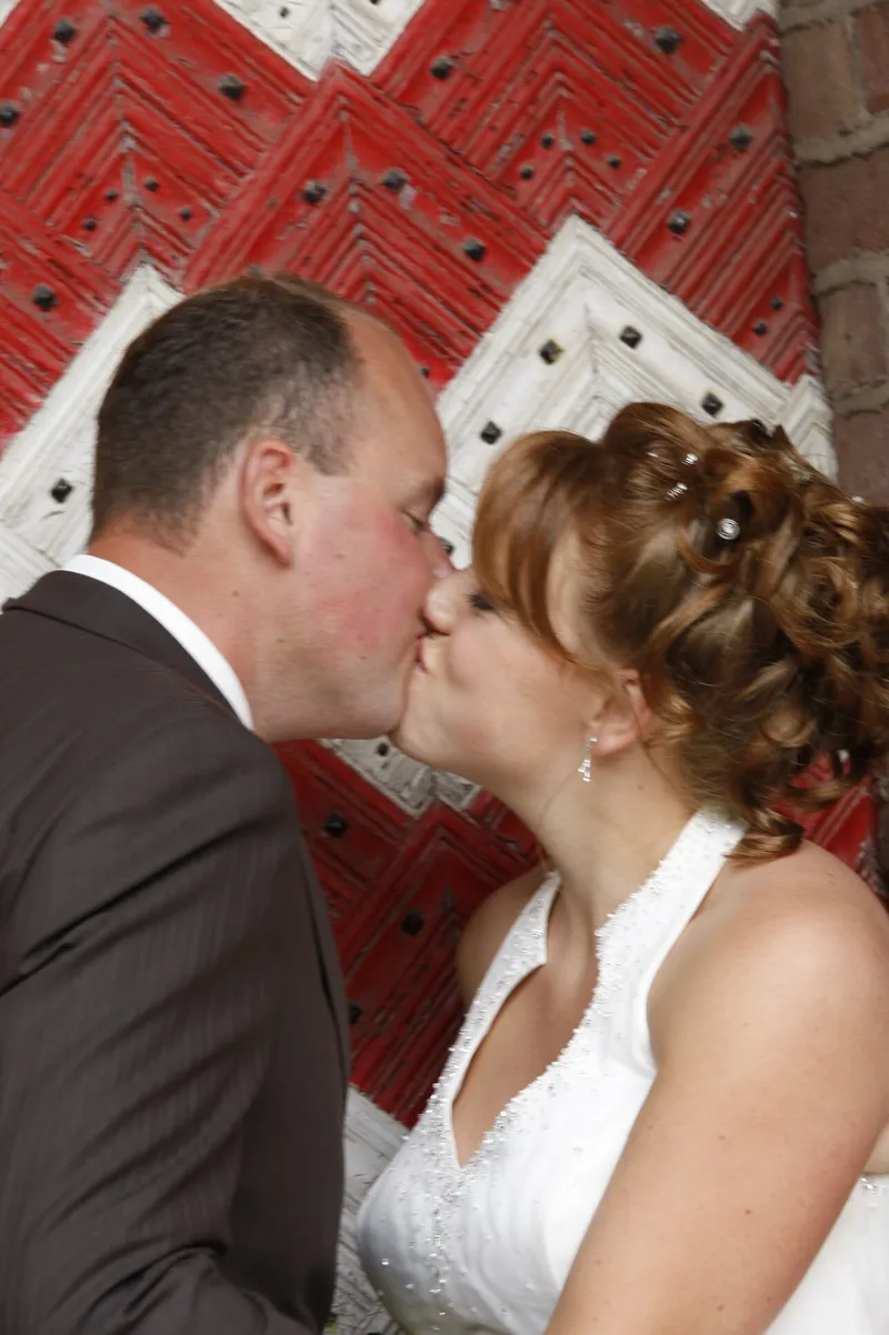 Yvonne en Robert-Jan kussen elkaar voor een rood-witte deur