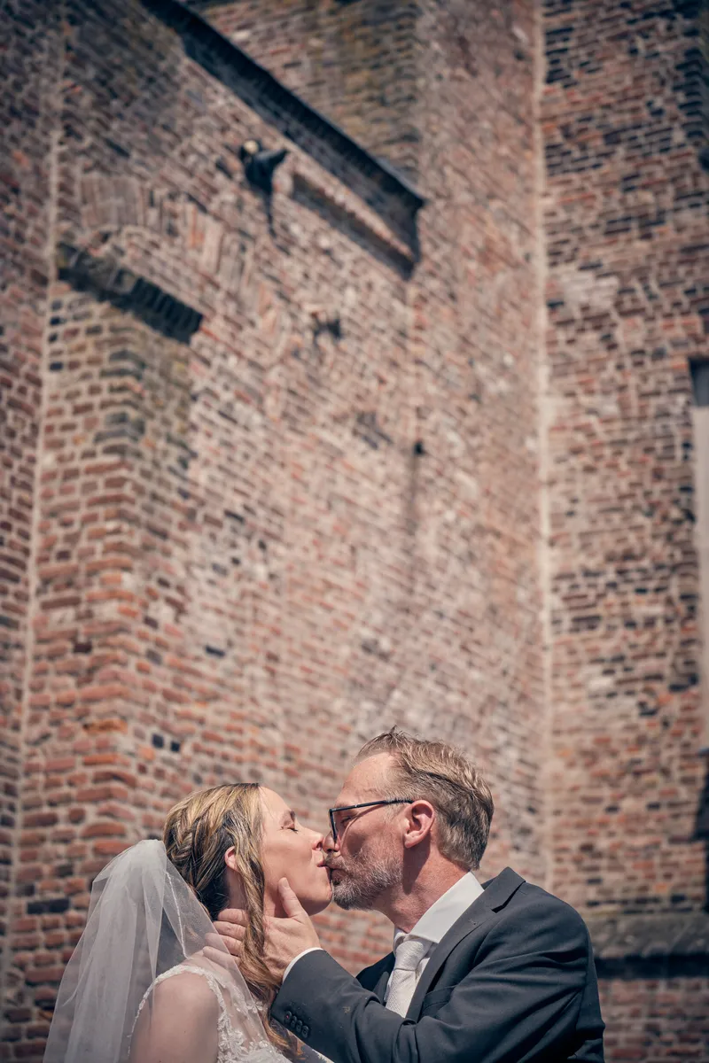 Mike en Ilja kussen elkaar tegen de bakstenen muur van het kasteel