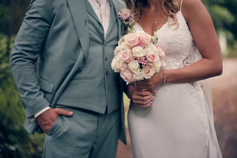Het boeket met roze rozen tussen het pak van Dennis en de jurk van Kim